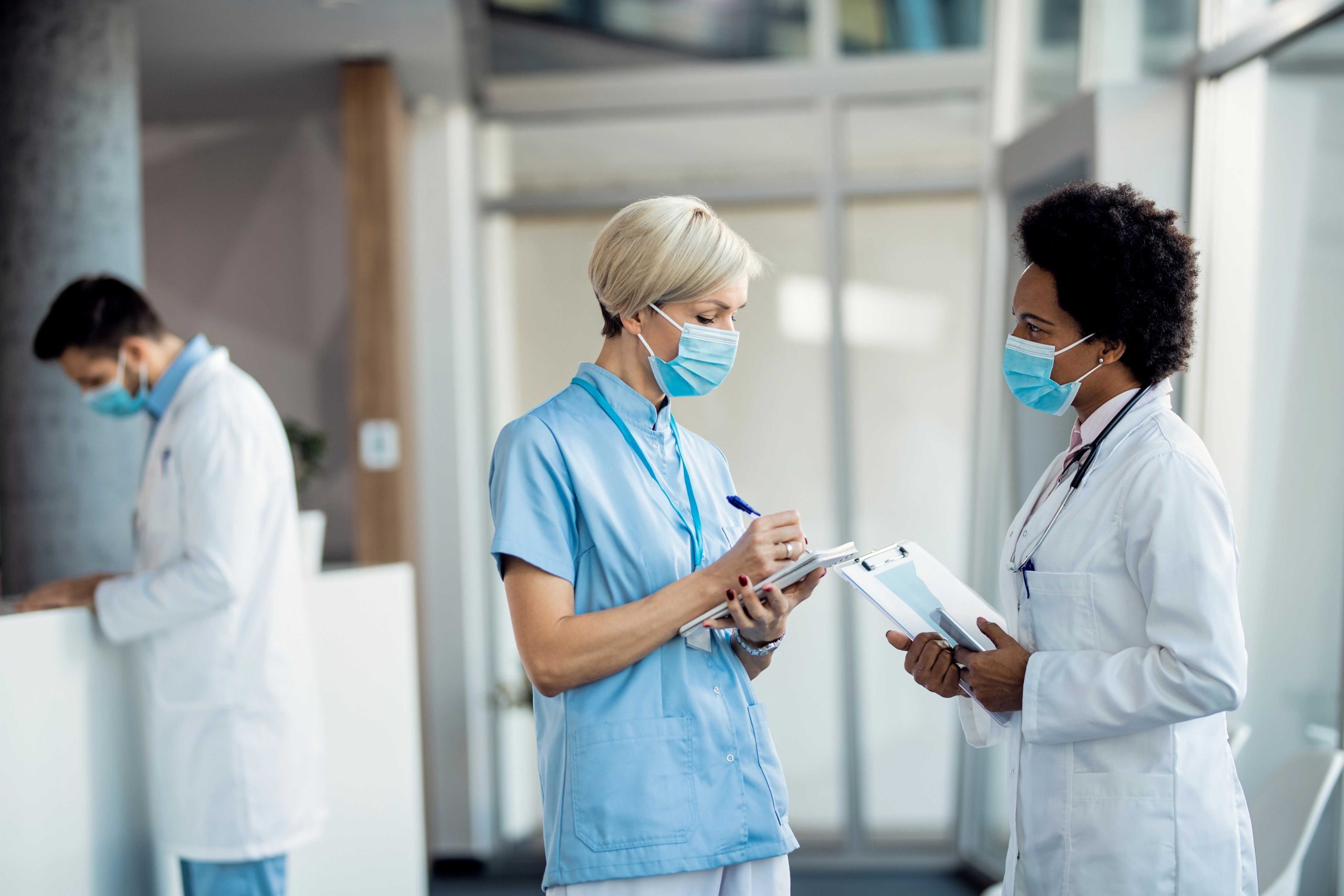 Credentialing: compressed african american female doctor talking nurse hallway medical clinic scaled